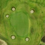 A stunning aerial view of a green at Galway Bay Golf, surrounded by four strategically placed sand bunkers. The well-manicured putting surface blends seamlessly with the surrounding fairway, while the natural rough and subtle undulations add to the challenge. This beautifully designed hole offers a scenic and demanding test for golfers.