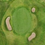 A stunning aerial view of a green at Galway Bay Golf, surrounded by three strategically placed sand bunkers. The smooth putting surface is nestled within the natural contours of the fairway, blending seamlessly with the surrounding rough. The layout offers both a scenic and challenging approach for golfers navigating this beautifully designed hole.